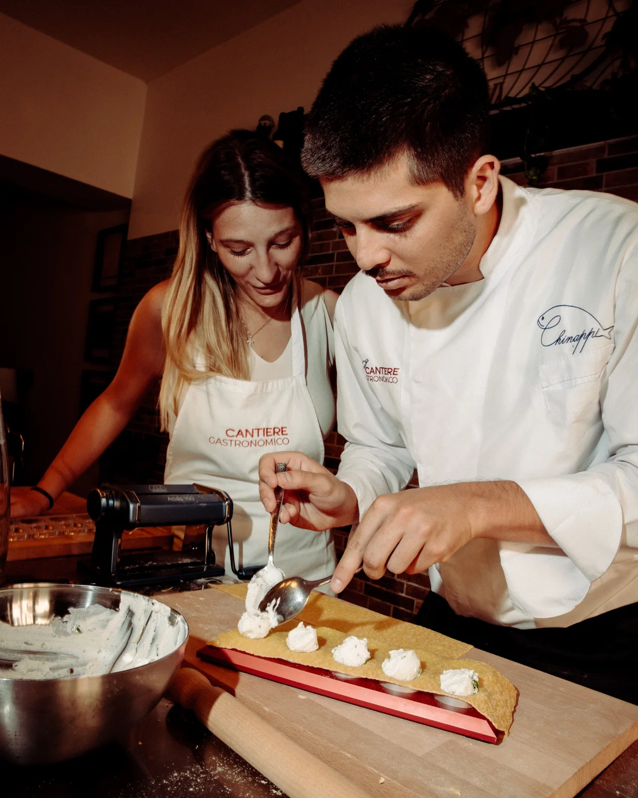 Chef and guest filling ravioli at the counter